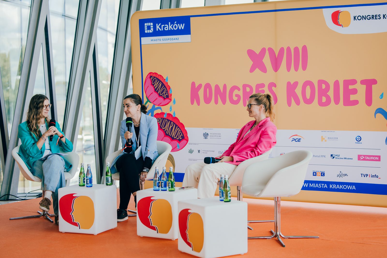 Alicja Szaraniec in a panel discussion at the XVIII Kongres Kobiet in Kraków, in front of the congress banner